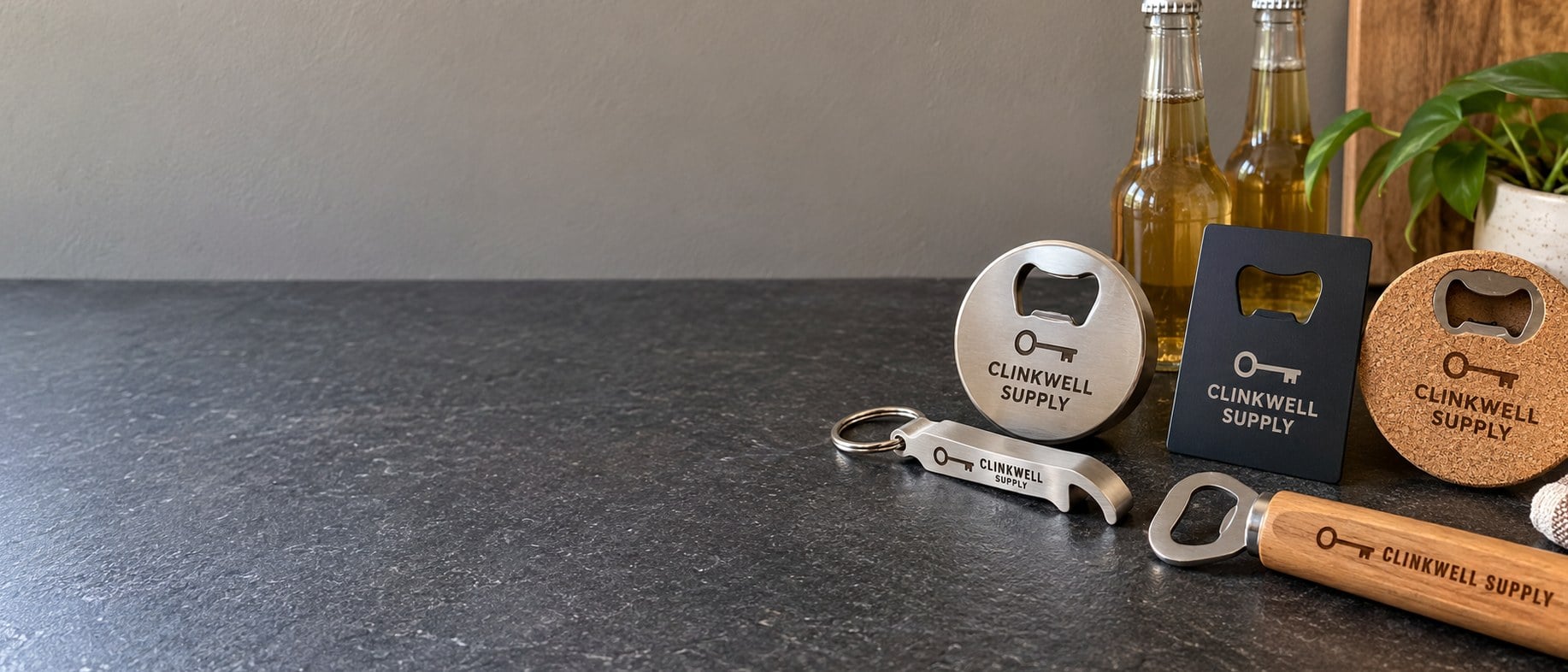 Custom engraved bottle openers laid out on a dark slate counter